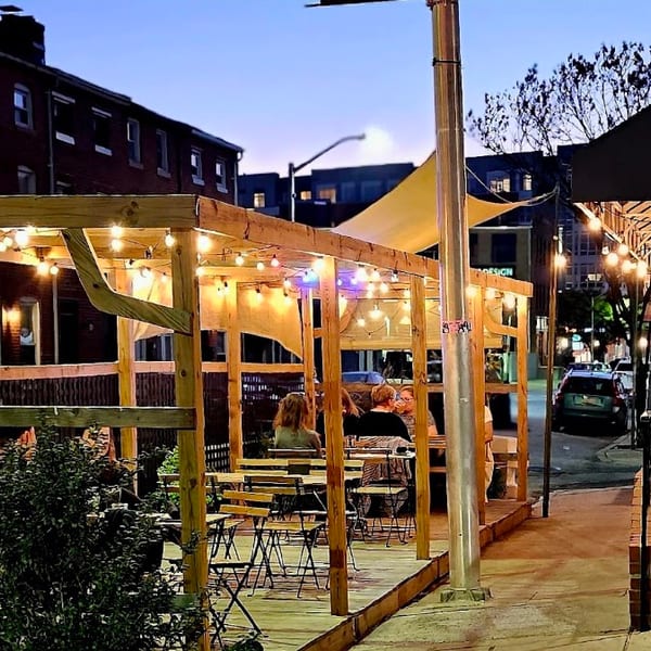 Sobo Cafe's outdoor patio at dusk, illuminated by string lights, with people dining.