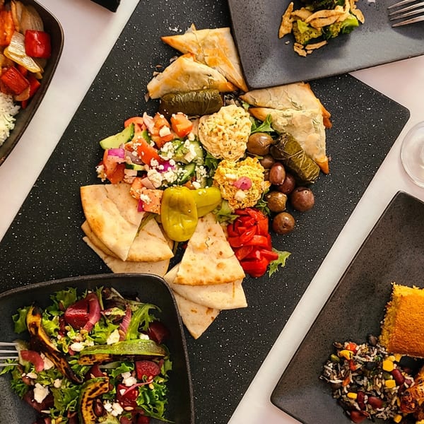 Overhead view of a table laden with various Mediterranean dishes and glasses of red wine.